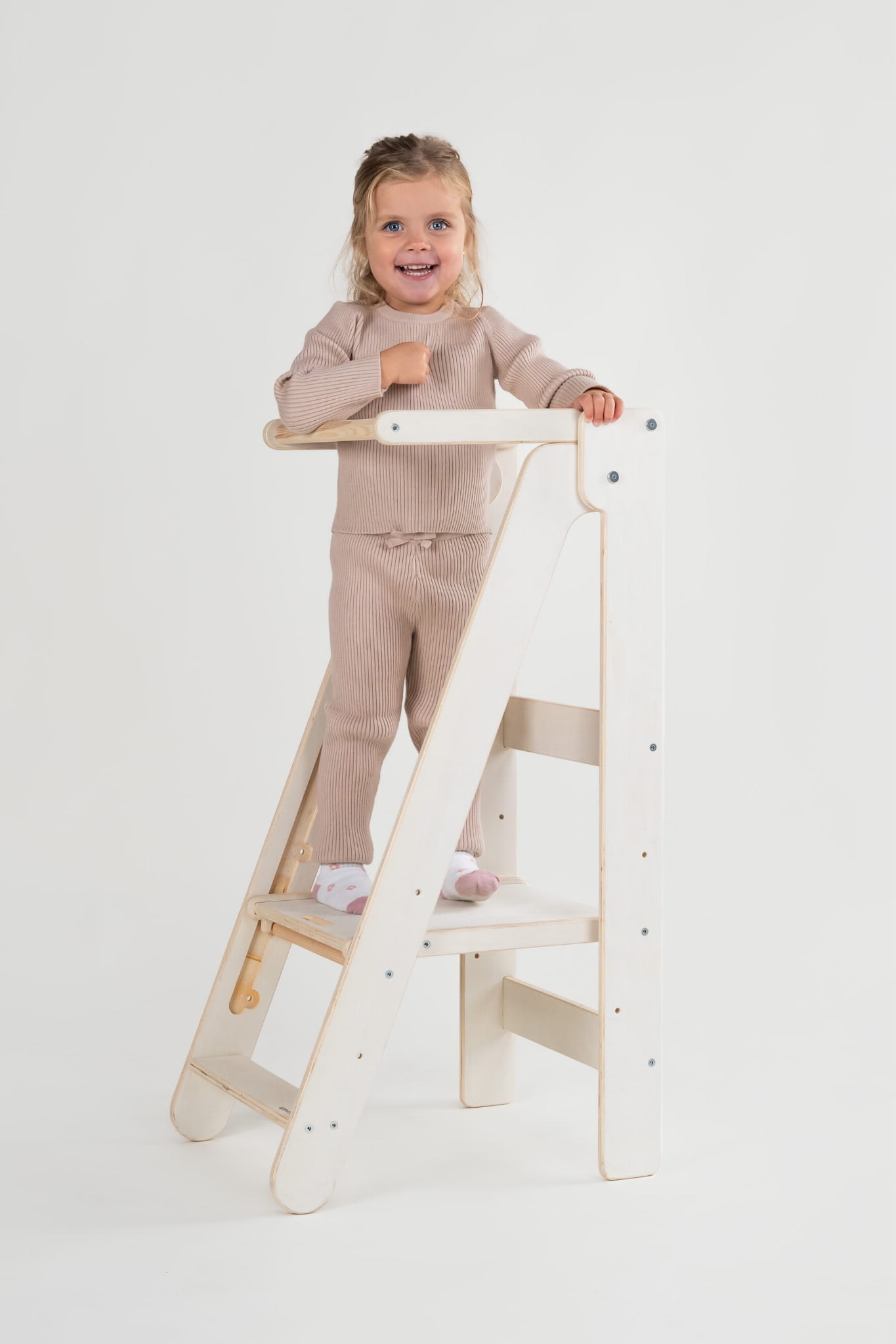 Radosna dziewczynka stoi na schodku składanego kitchen helpera